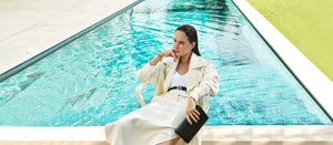 Woman in a white outfit sitting by a pool, cali clutch, YY belt, bracelet lulu, YY earrings