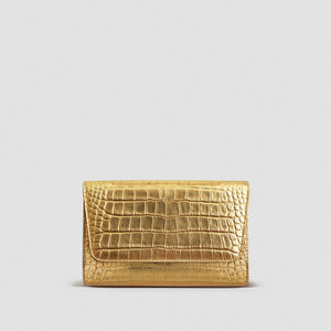 A gold-toned crocodile-embossed leather clutch or wallet, centered against a solid light gray background.