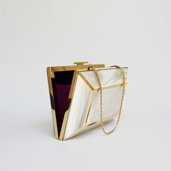 YLIANA YEPEZ Minaudiere. Rectangular clutch with gold frame and beige interior on a white background